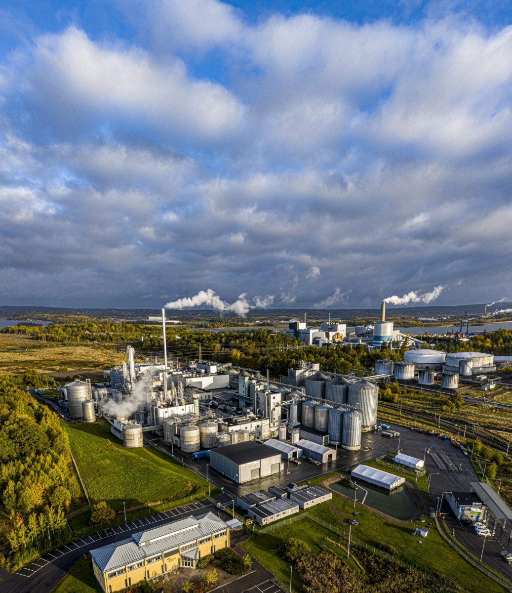 Bild på stor fabrik ovanifrån i vackert landskap